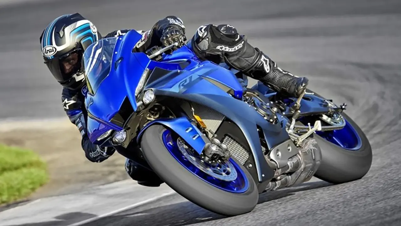 A motorcyclist riding a blue Yamaha YZF-R1 on the road